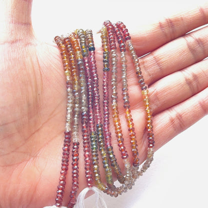 A person holds delicate strands of tundra sapphire beads.