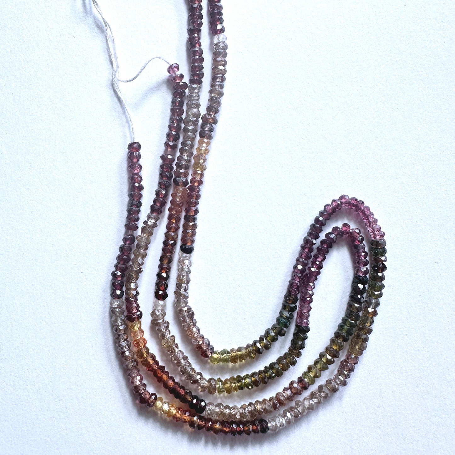 Tundra Sapphire gemstone beads in faceted rondelle cut reflect light with organic brilliance.