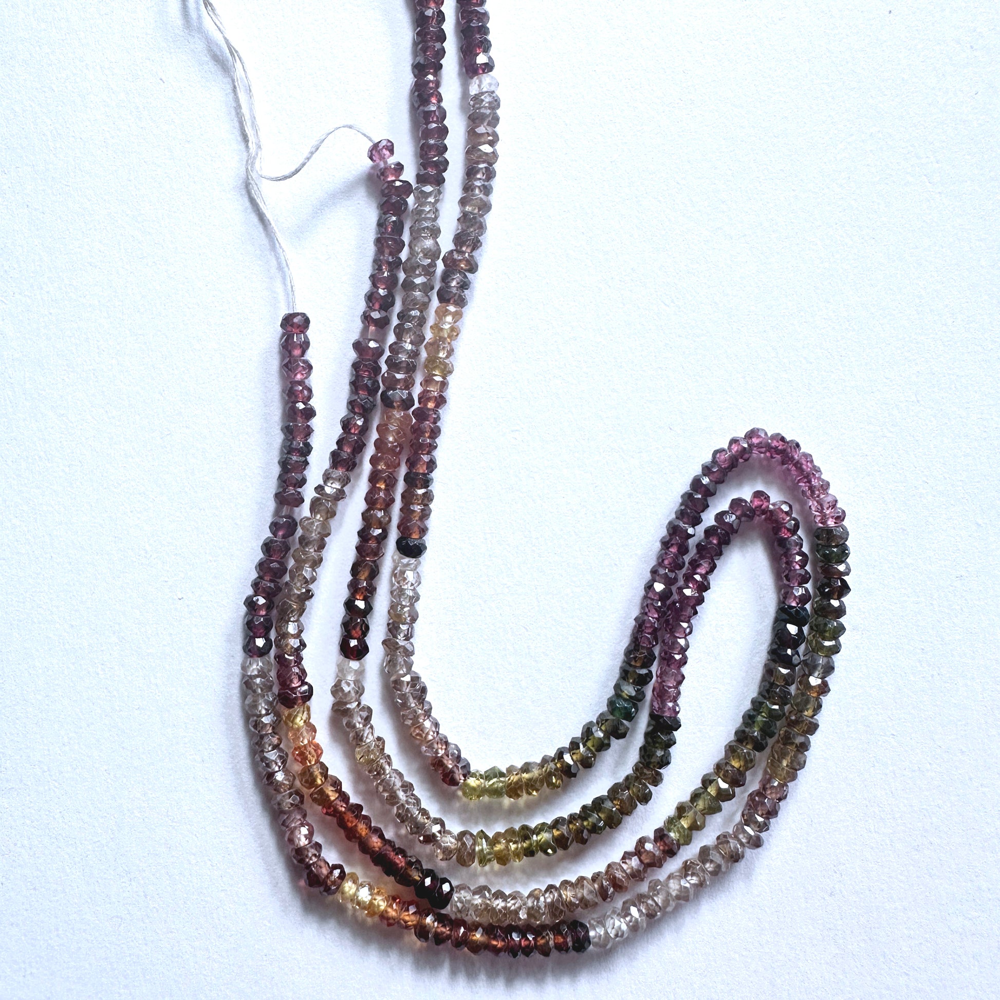 Tundra Sapphire gemstone beads in faceted rondelle cut reflect light with organic brilliance.