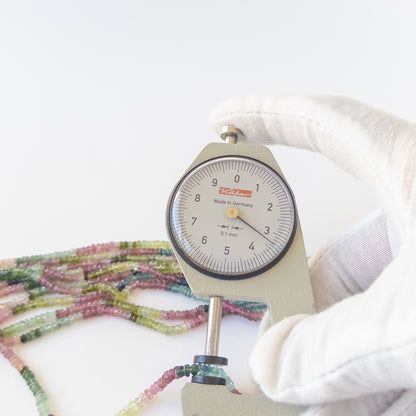 A dial gauge measures the Watermelon Tourmaline faceted rondelle 2.8–3.5mm gemstone.