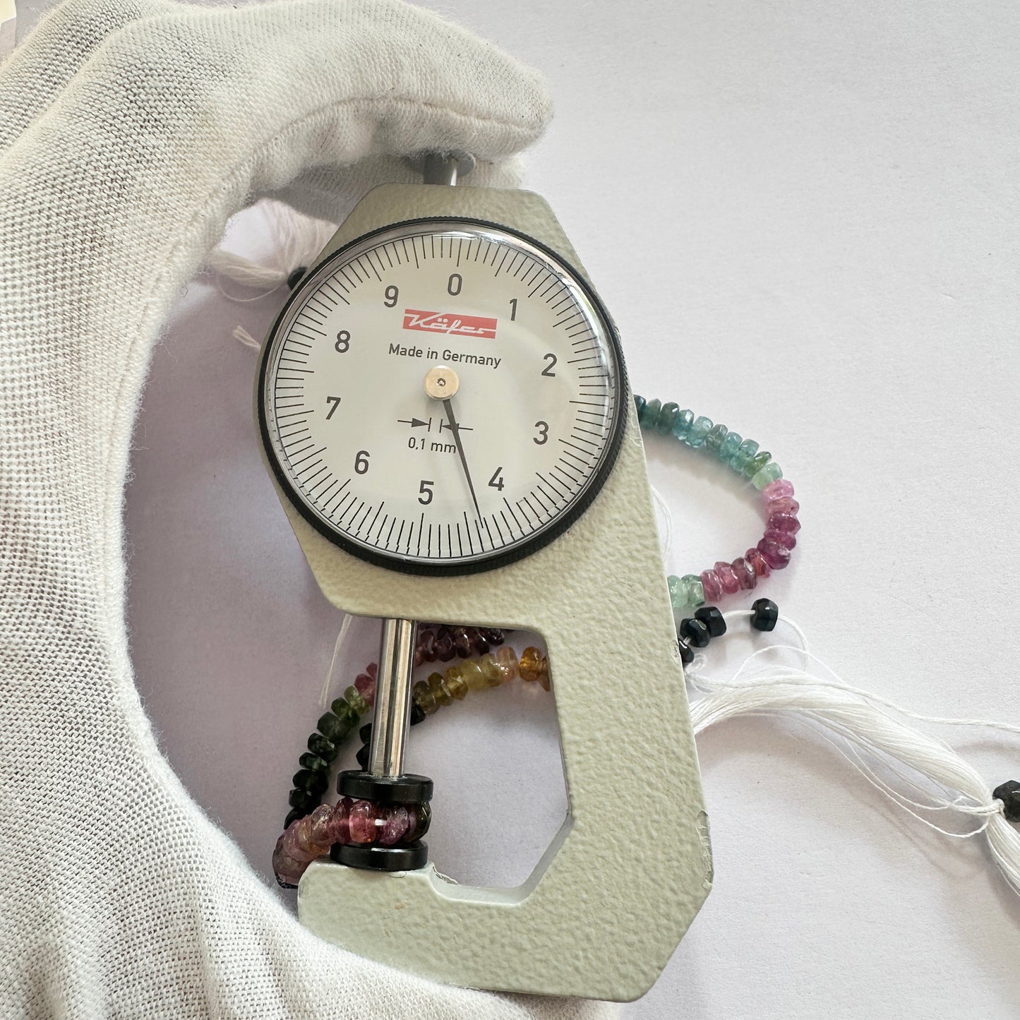 A dial gauge measures the Watermelon Tourmaline faceted rondelle 4.5mm gemstone, ensuring accurate bead sizing.