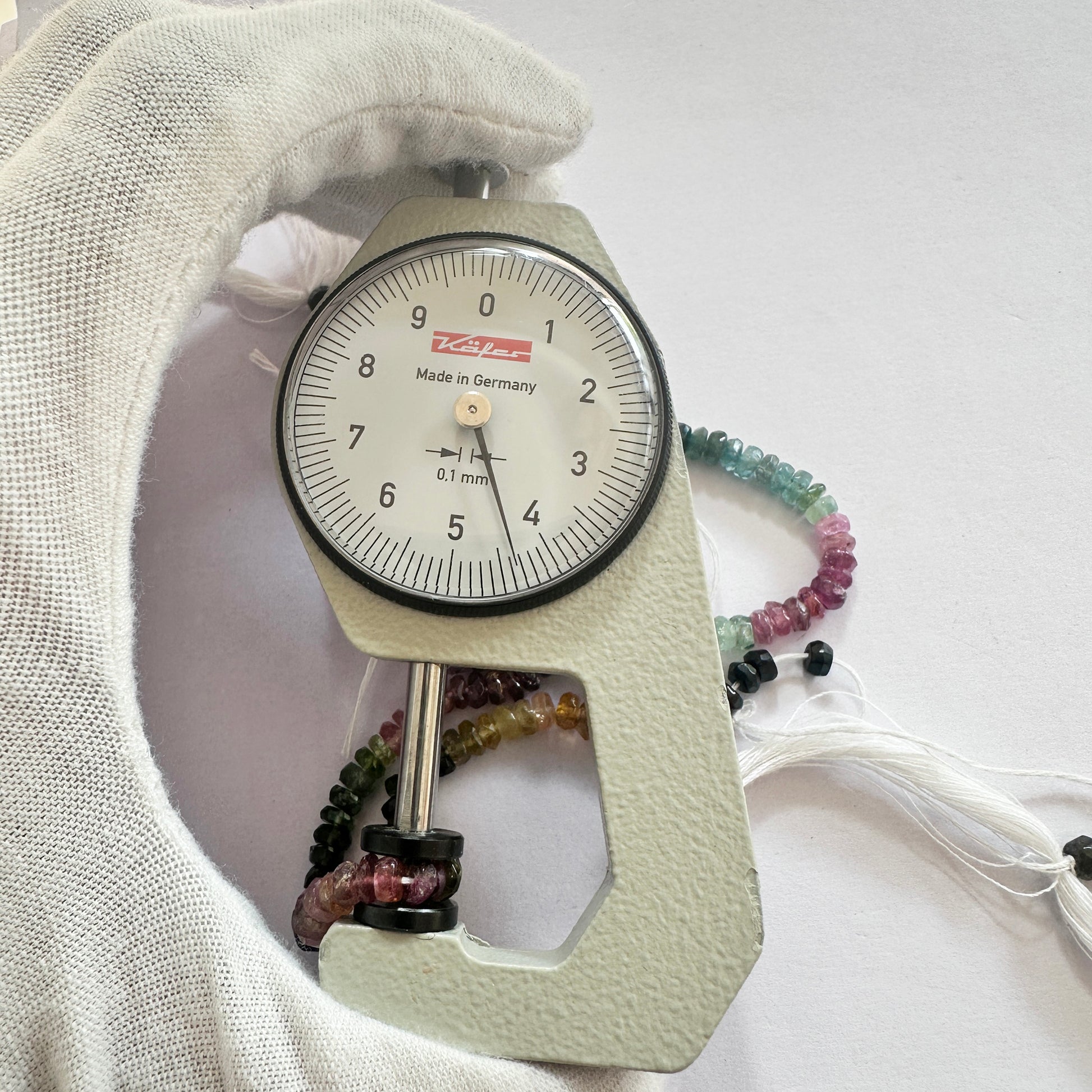 A dial gauge measures the Watermelon Tourmaline faceted rondelle 4.5mm gemstone, ensuring accurate bead sizing.