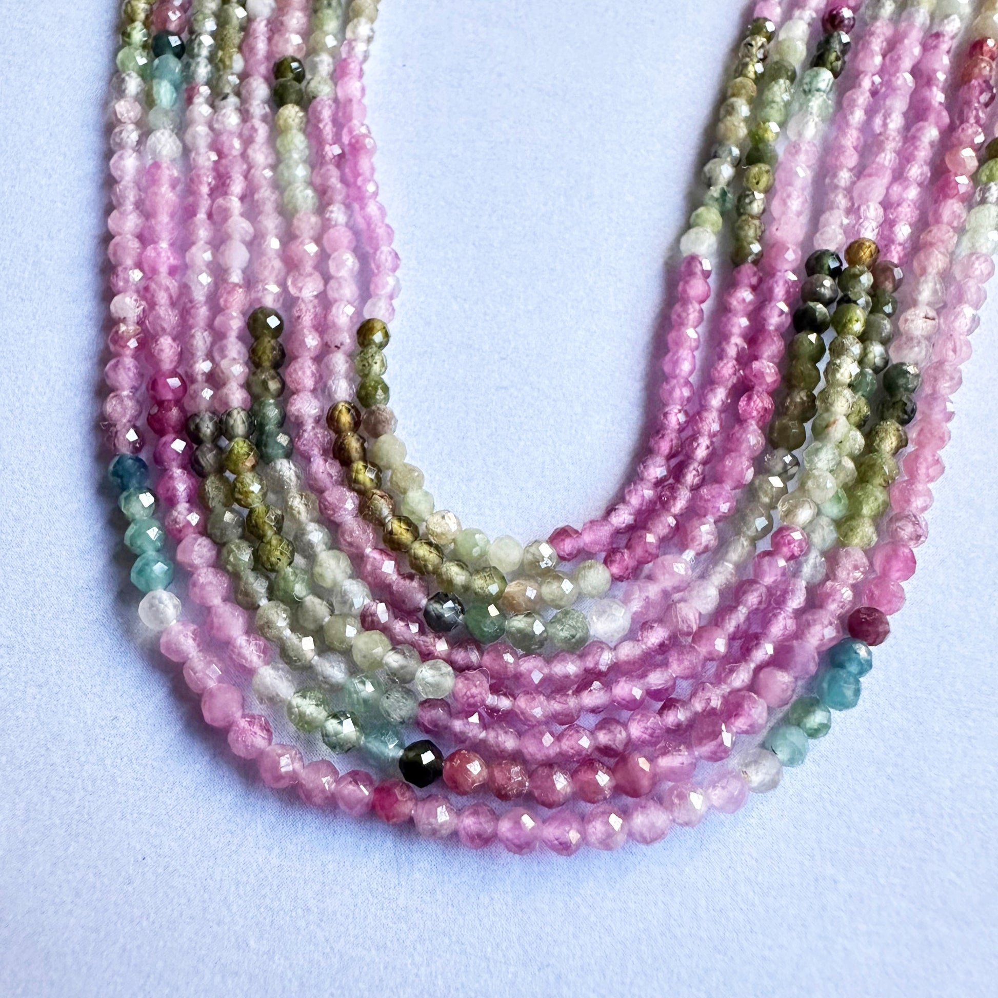 Close-up of watermelon tourmaline faceted rondelle beads showing vivid pink and green hues.