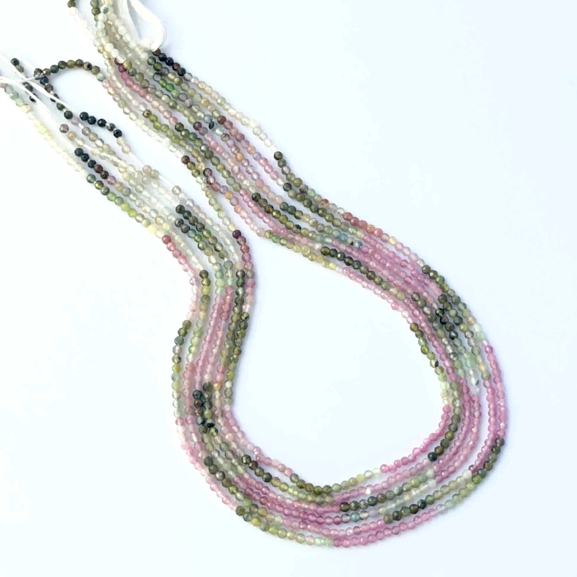 Close‑up of Watermelon Tourmaline stone beads arranged in a strand with polished faceted surfaces.