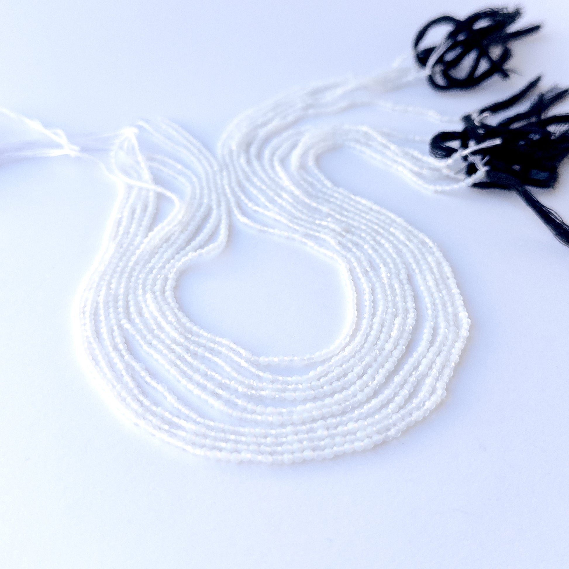 Close‑up of genuine White Chalcedony faceted rondelle beads showing their shine, clarity, and delicate 2.1mm cut.