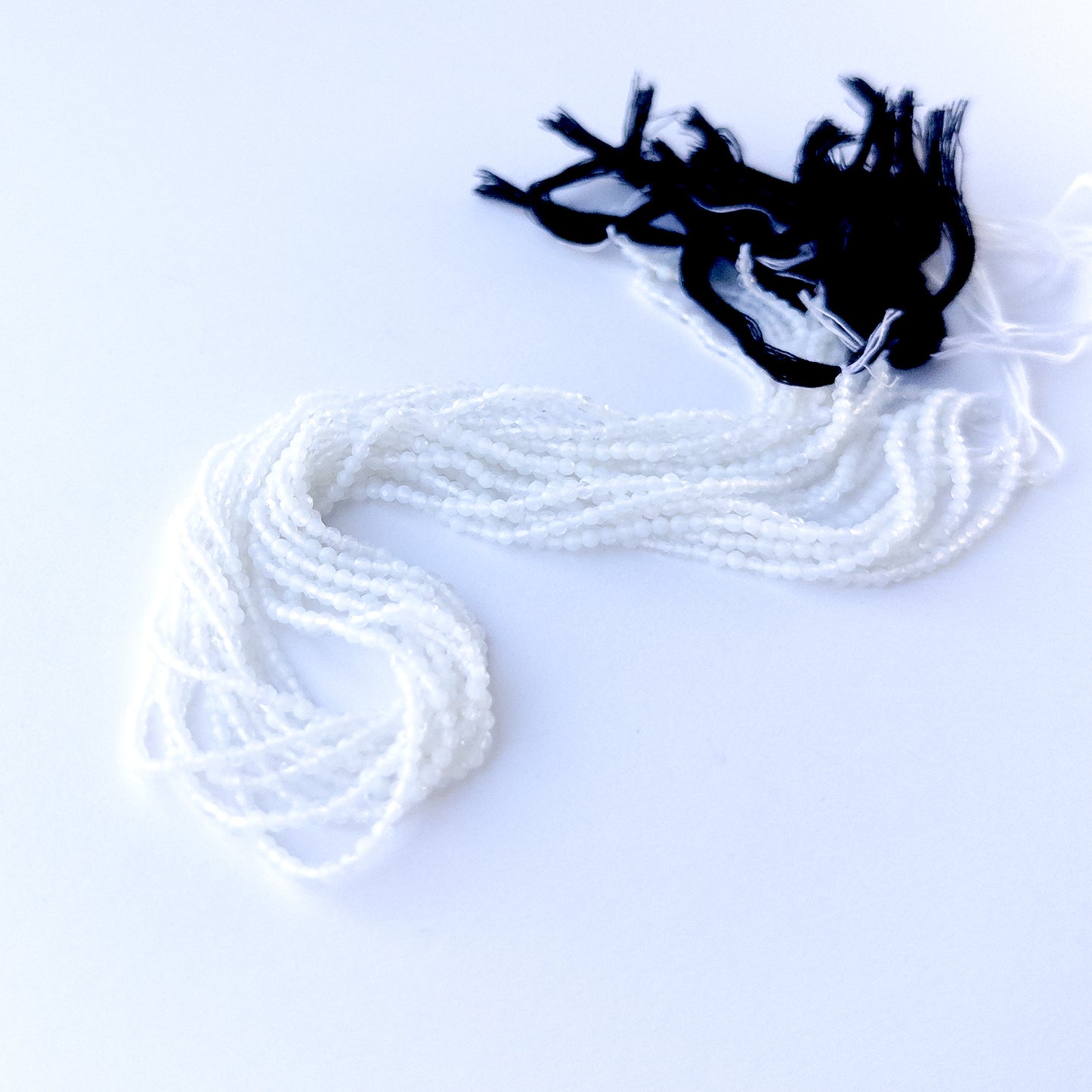 delicate strands of White Chalcedony beads, showcasing their faceted rondelle design and sparkle.  
