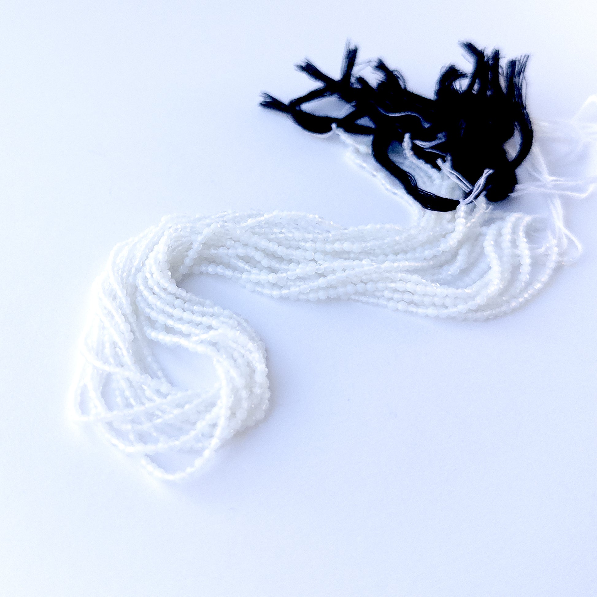 delicate strands of White Chalcedony beads, showcasing their faceted rondelle design and sparkle.  