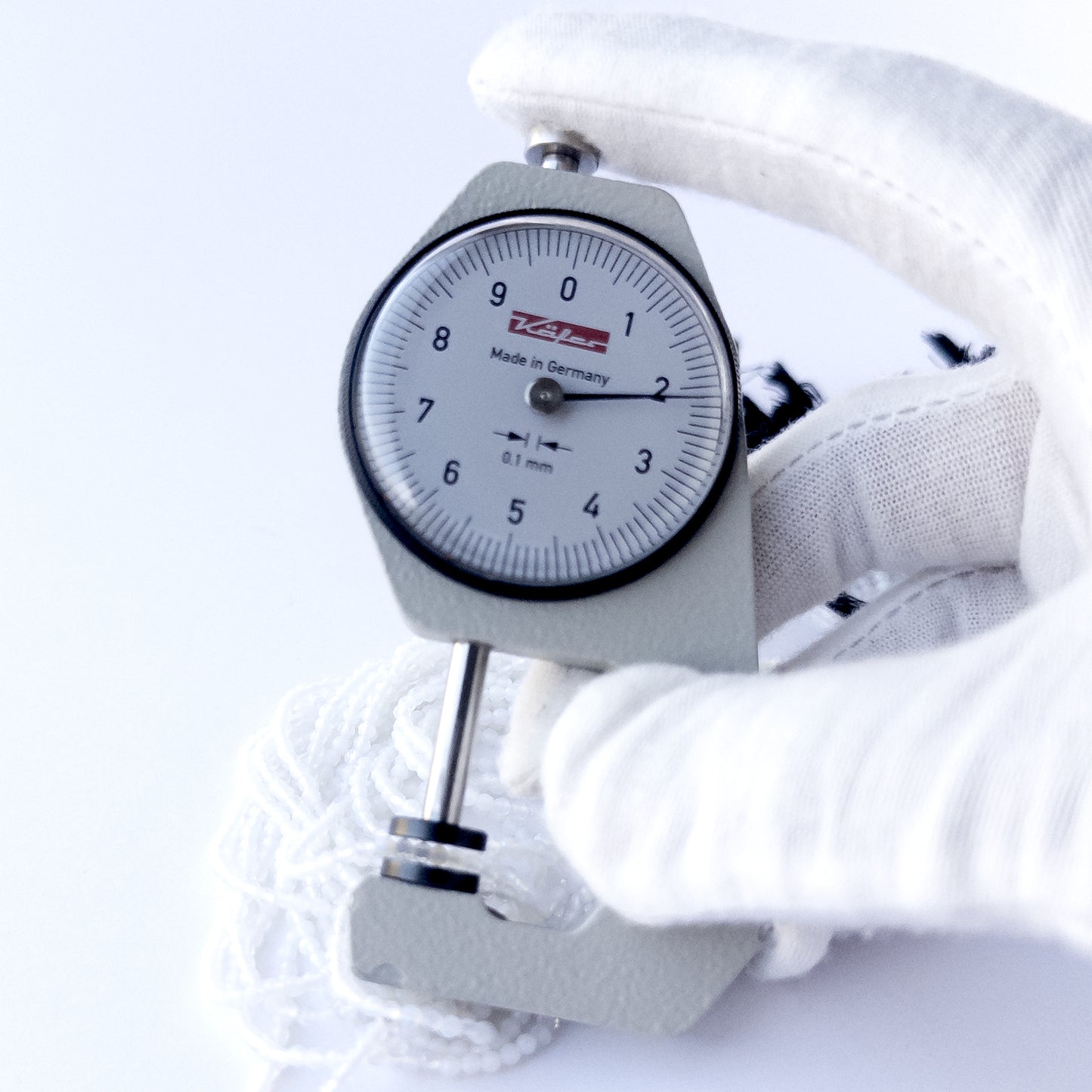 A dial gauge measures the White Chalcedony faceted rondelle 2.1mm gemstone.