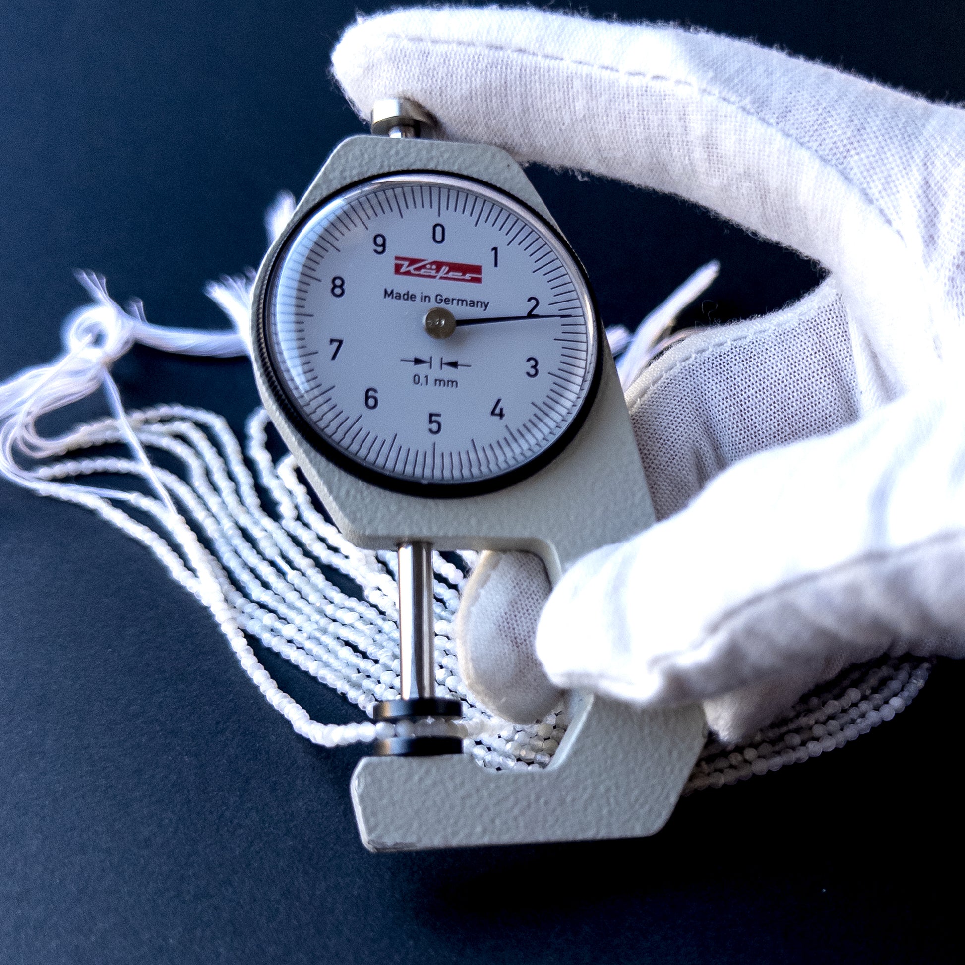 A dial gauge measures the White Opal faceted rondelle 2.2mm gemstone.
