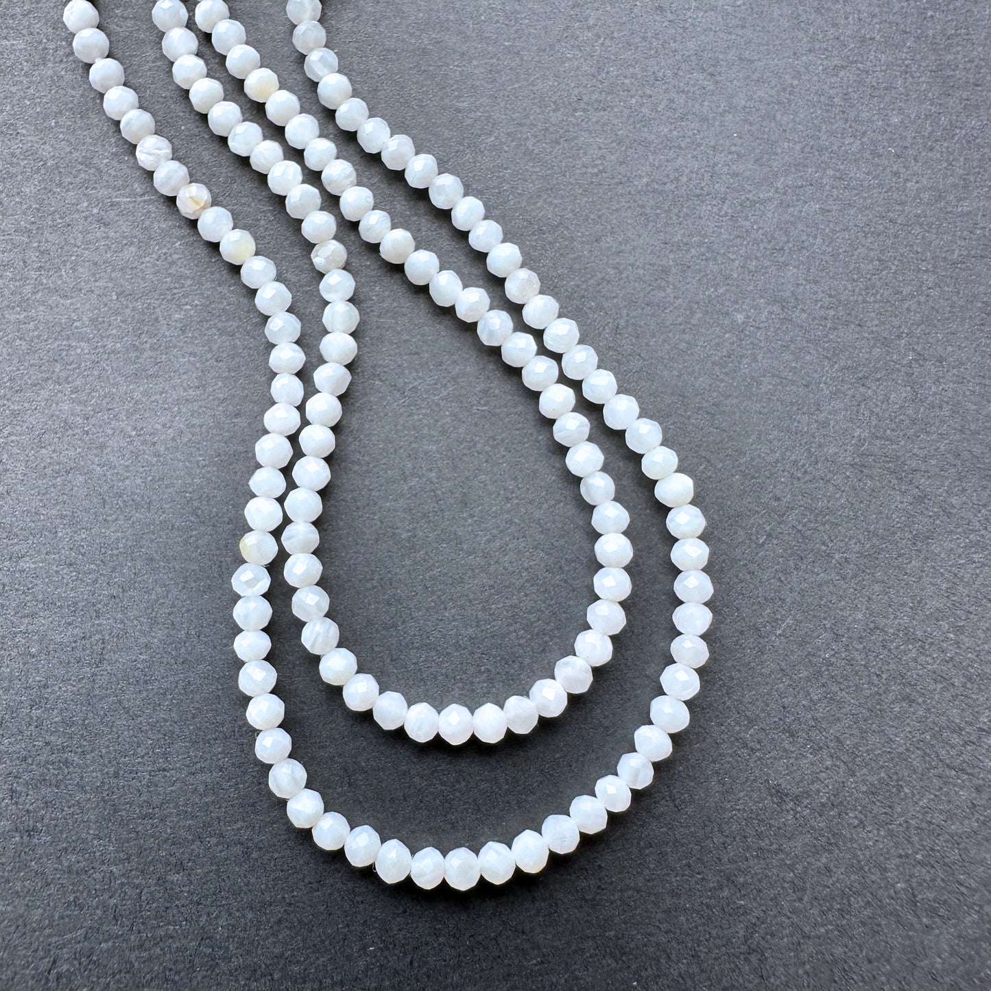 White Opal faceted rondelle beads with soft milky tones arranged on a 32cm strand for jewellery making.