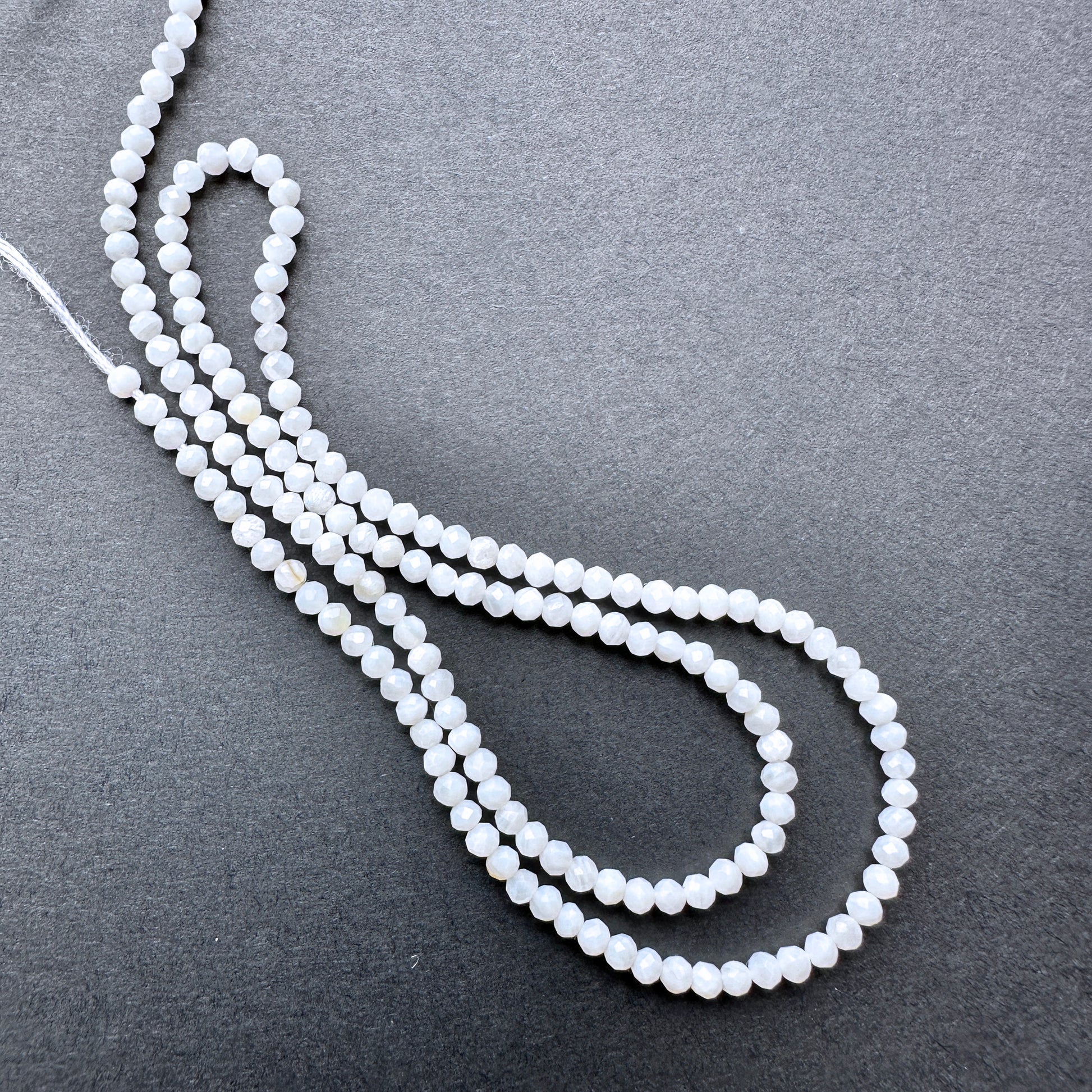 A dial gauge measures the White Opal faceted rondelle 2.4mm gemstone.