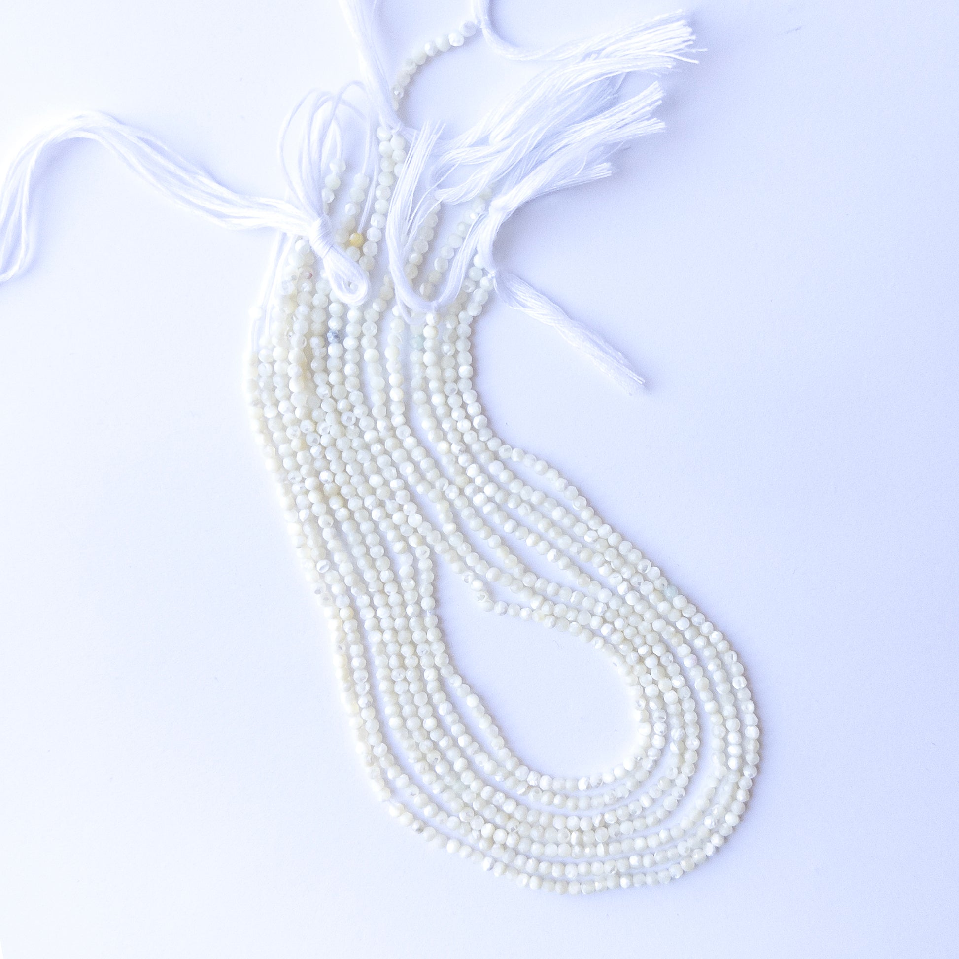 Genuine White Opal gemstone beads displaying soft milky tones, polished facets, and a neatly arranged 31cm strand for jewellery design.