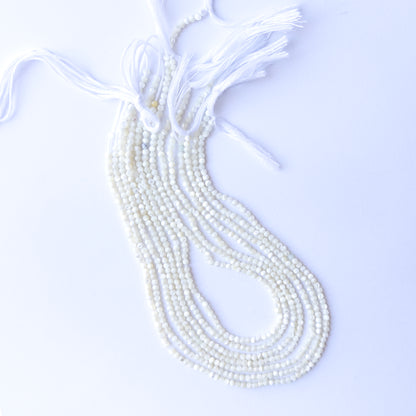 Genuine White Opal gemstone beads displaying soft milky tones, polished facets, and a neatly arranged 31cm strand for jewellery design.