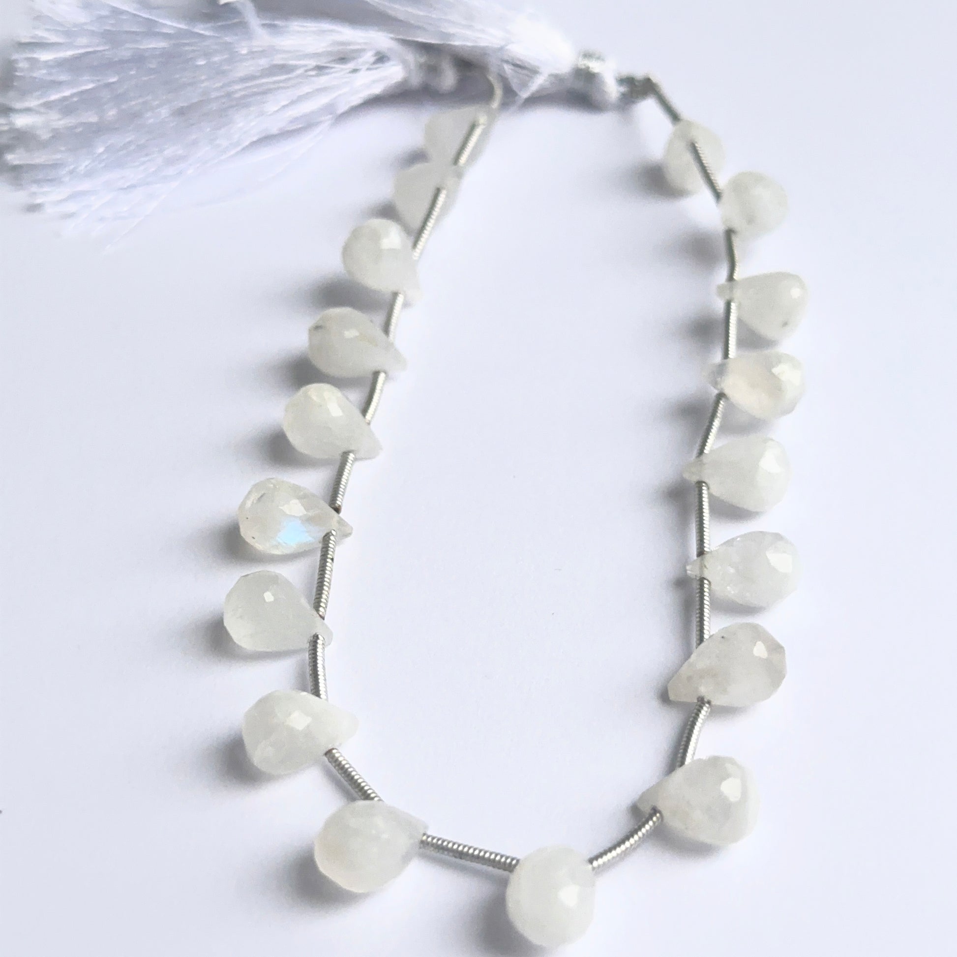 Close-up of rainbow moonstone briolette beads highlighting their iridescent glow and polished facets.