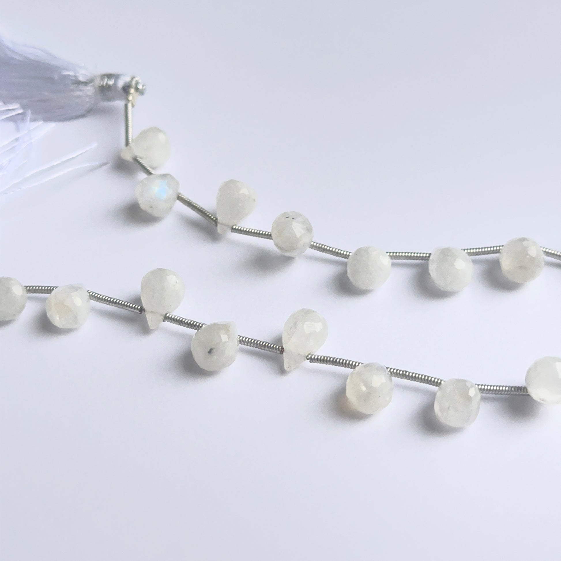 White rainbow moonstone briolettes photographed to show clarity, sparkle, and natural gemstone beauty.