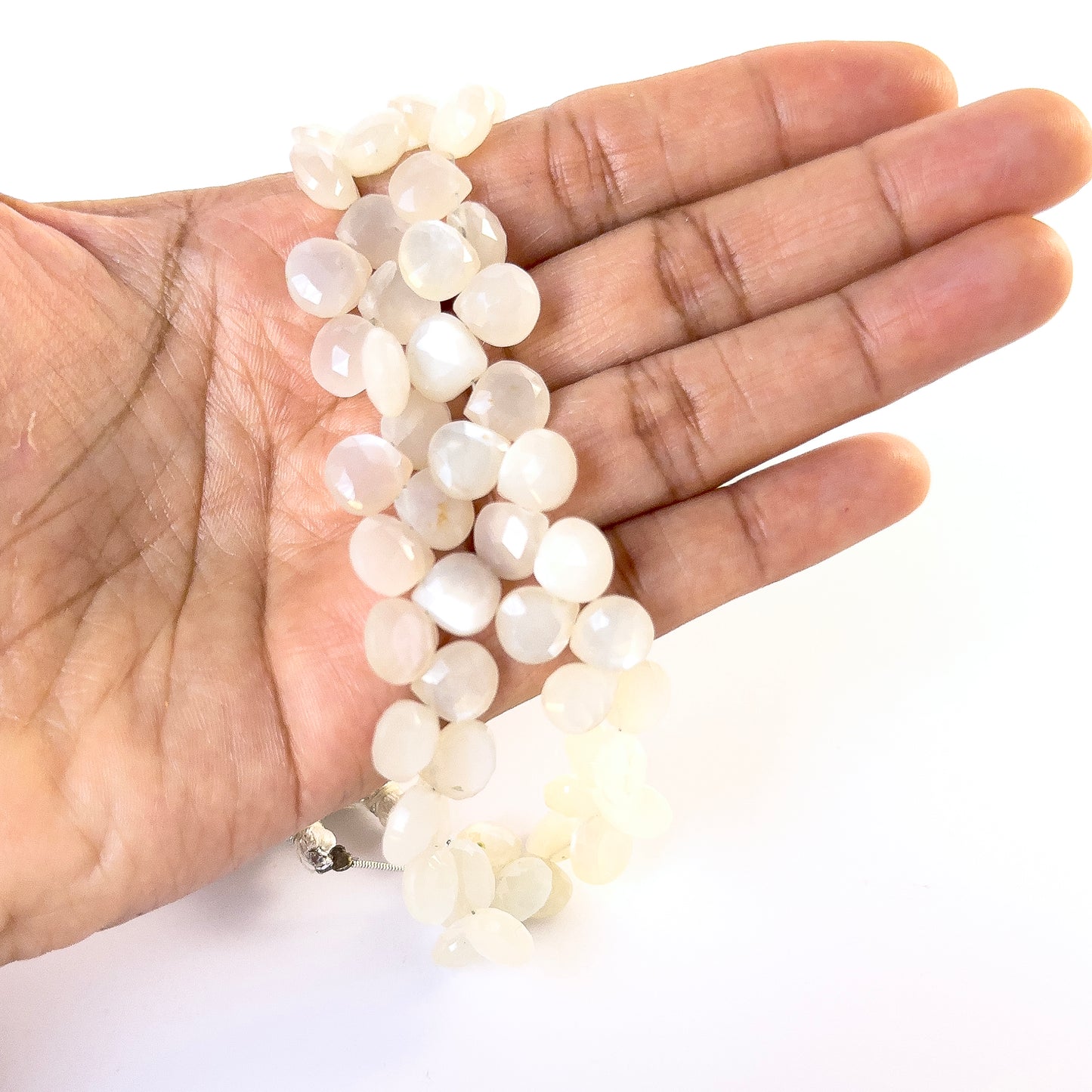A person holds delicate strands of White Rainbow Moonstone faceted briolette beads, showcasing their cut design.