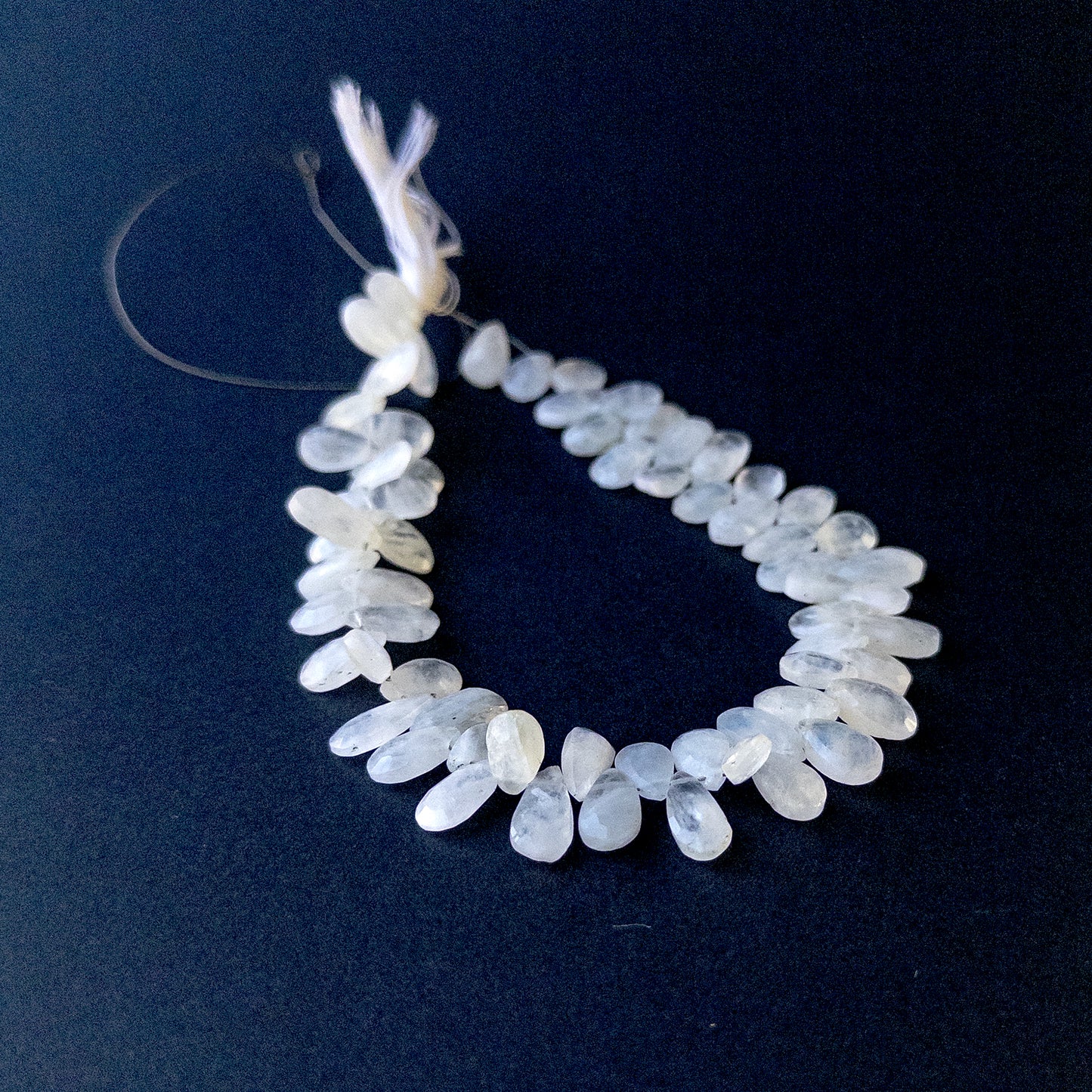 White Rainbow Moonstone faceted briolette pear beads arranged on a 27cm strand with natural glow for handmade jewellery components.