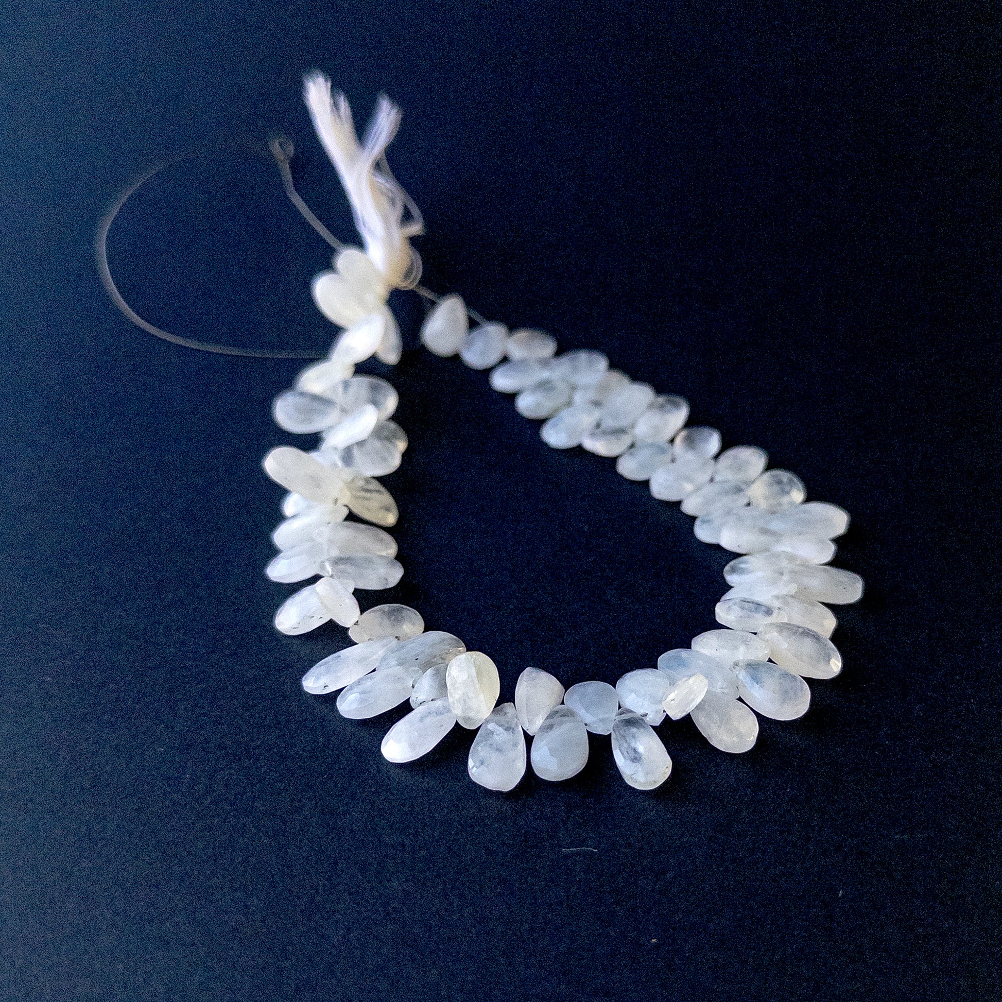 White Rainbow Moonstone faceted briolette pear beads arranged on a 27cm strand with natural glow for handmade jewellery components.