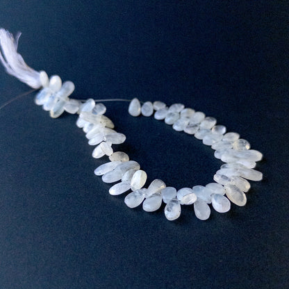 Close‑up of Rainbow Moonstone faceted briolette pear beads showing iridescent shimmer and polished facets.