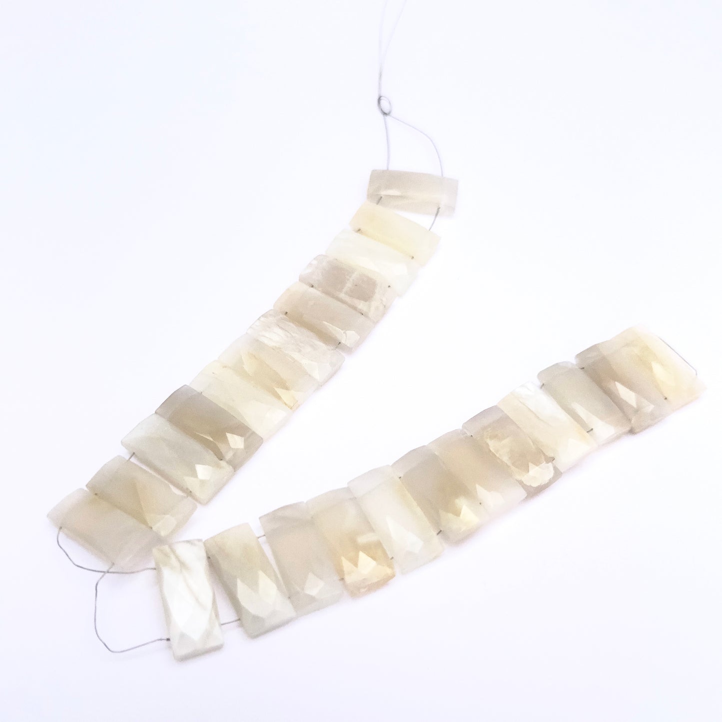 Close-up of White Rainbow Moonstone gemstone beads showing faceted cut and clarity.
