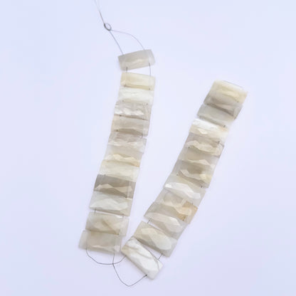 Natural White Rainbow Moonstone stone beads arranged in strands with subtle glow.
