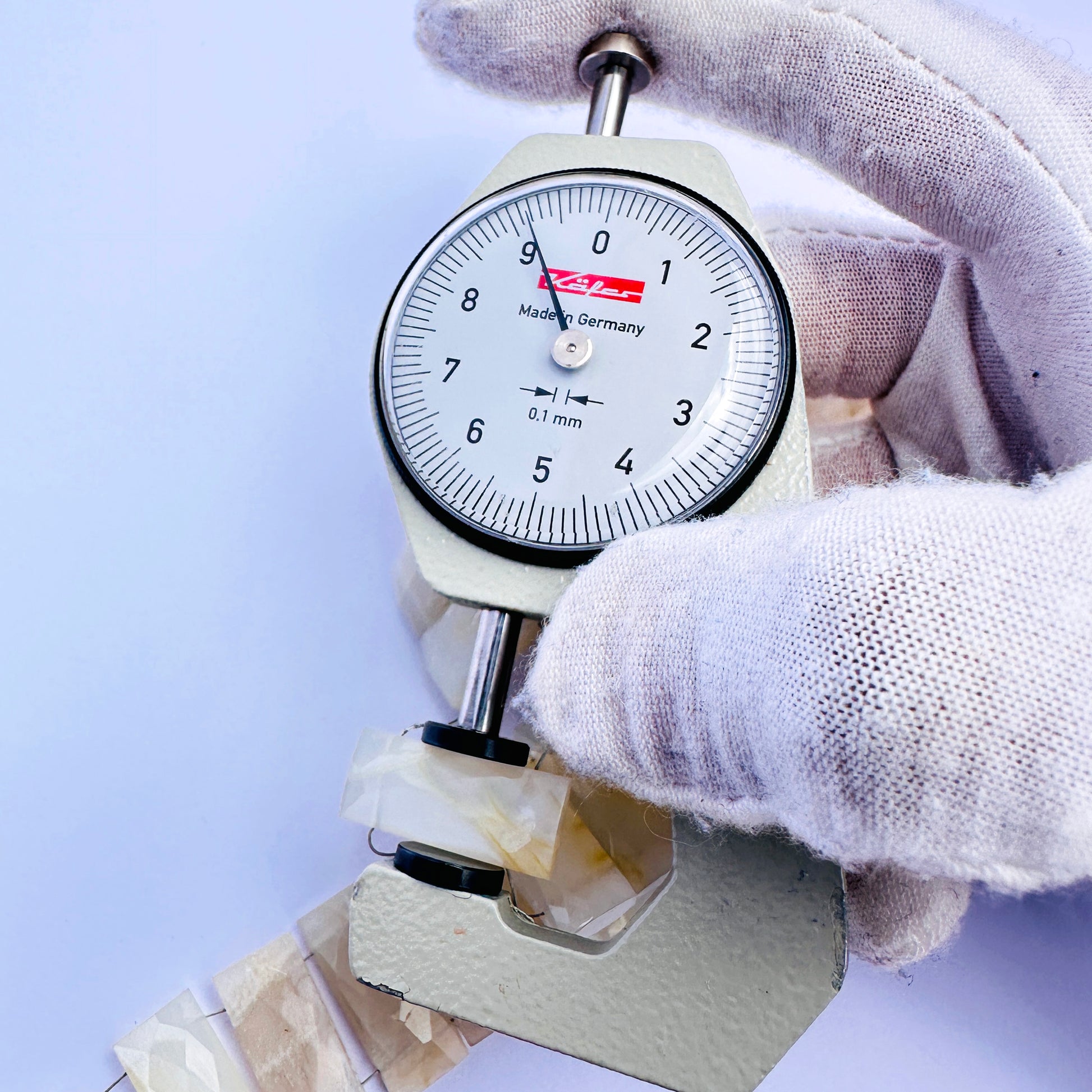A dial gauge measures the White Rainbow Moonstone faceted rectangle 20×9mm gemstone.