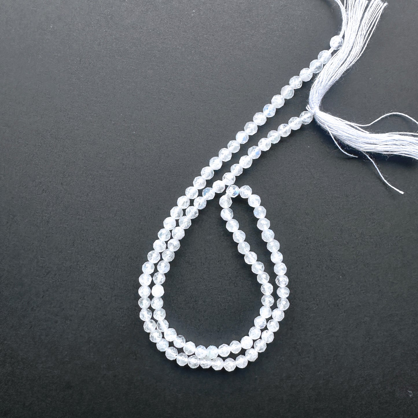 32cm strand of White Rainbow Moonstone gemstone rondelles arranged for DIY jewellery inspiration.
