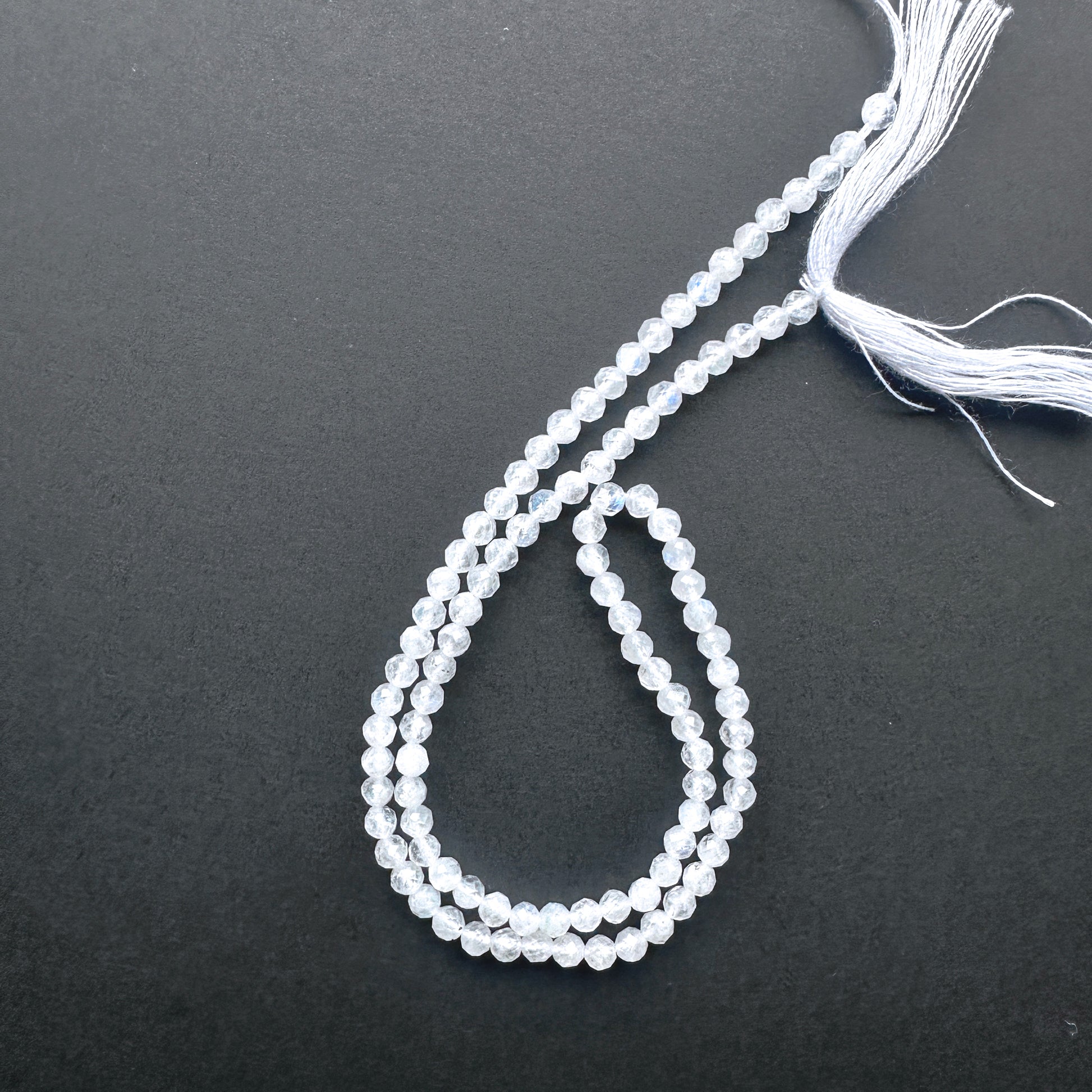 32cm strand of White Rainbow Moonstone gemstone rondelles arranged for DIY jewellery inspiration.