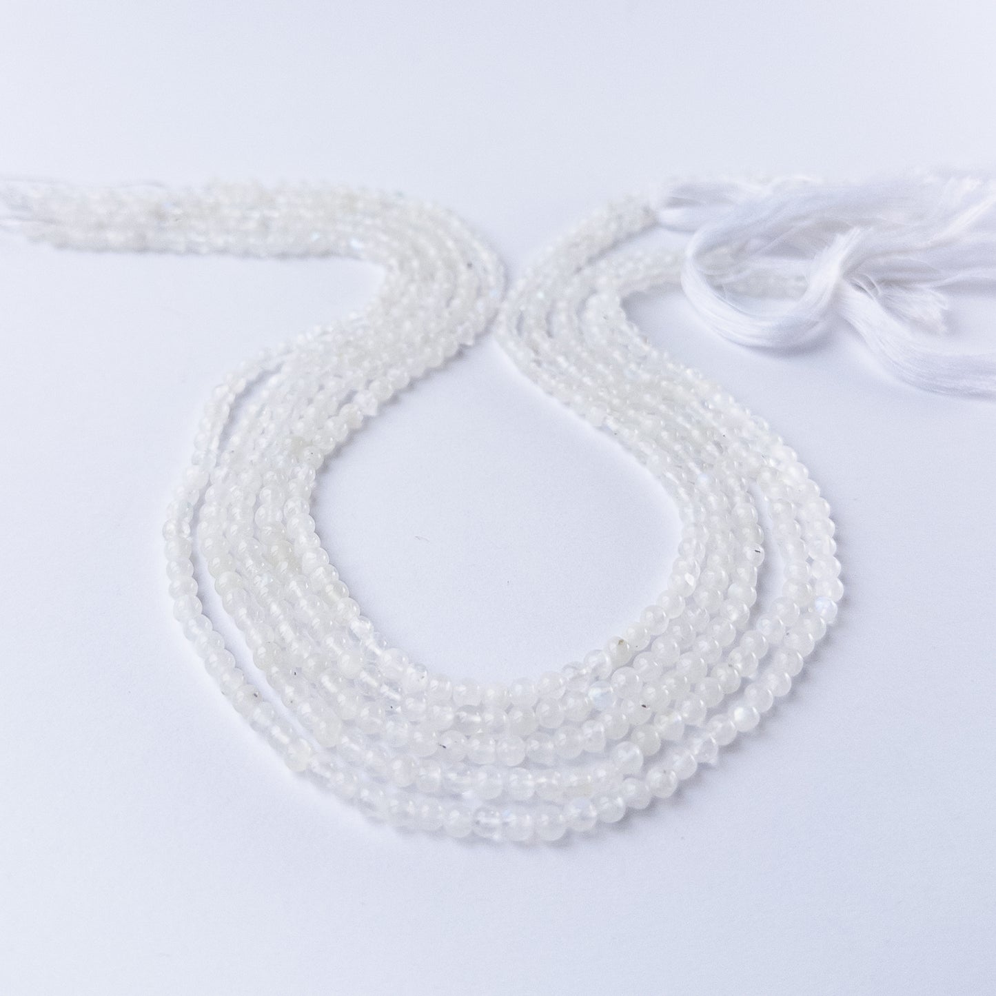 White Rainbow Moonstone smooth round gemstone beads in 3.5mm size arranged on a 33cm strand with soft glowing sheen.