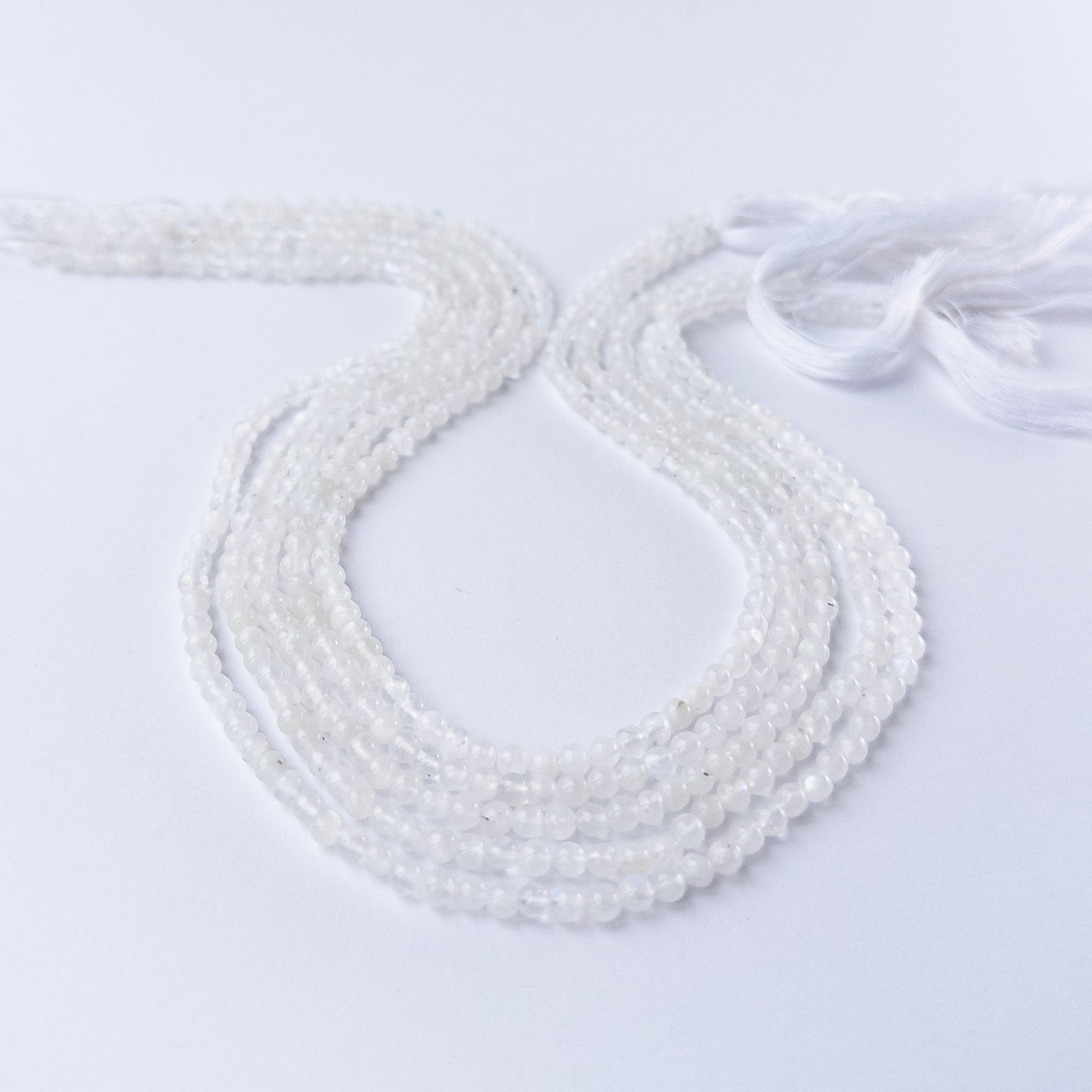 White Rainbow Moonstone smooth round gemstone beads in 3.5mm size arranged on a 33cm strand with soft glowing sheen.