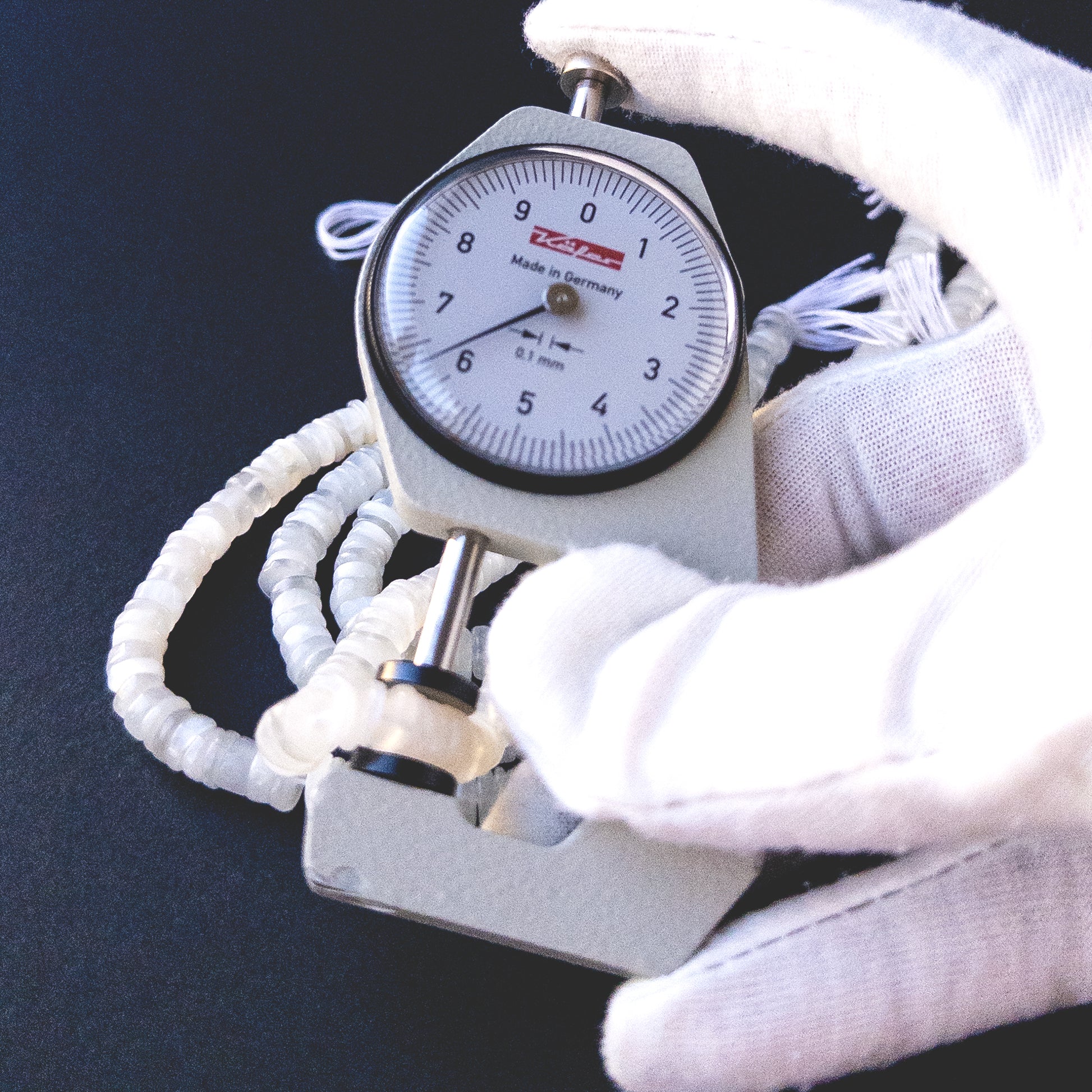 A dial gauge measures the White Rainbow Moonstone smooth wheel 6mm gemstone.