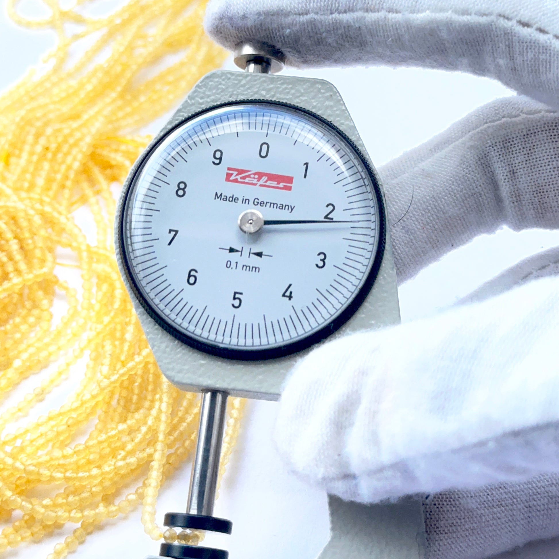 A dial gauge measures the yellow chalcedony faceted rondelle 2.2mm gemstone.