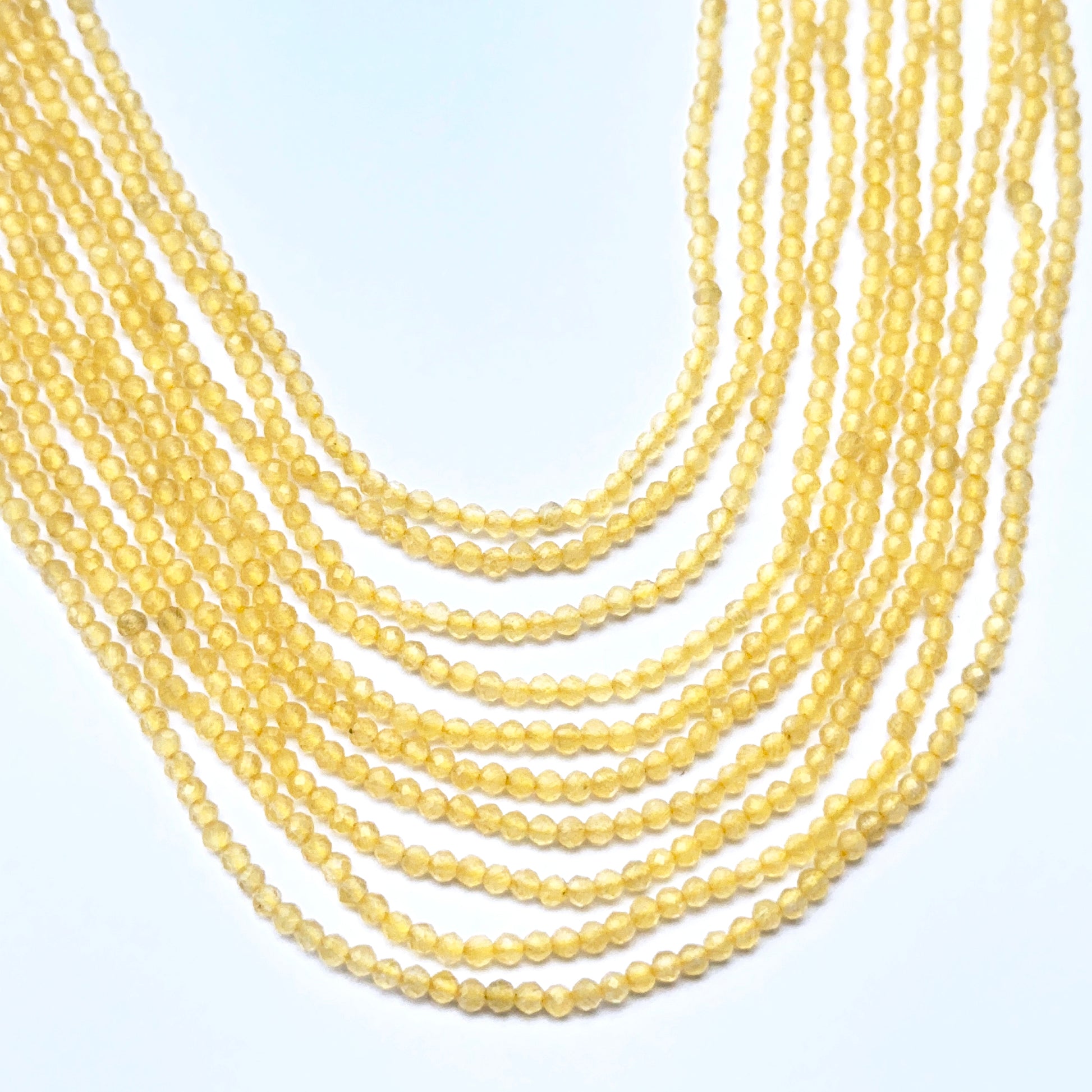 Close‑up of 2.2mm faceted yellow chalcedony beads arranged on a strand.