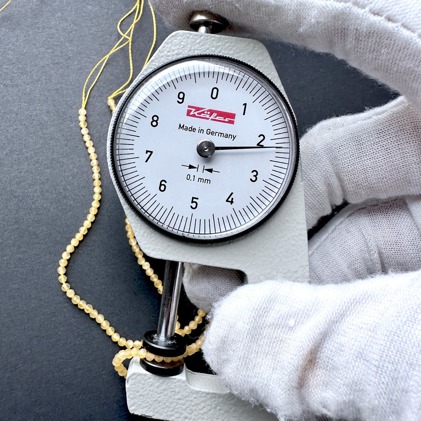 A dial gauge measures the Yellow Chalcedony faceted rondelle 2.2mm gemstone.