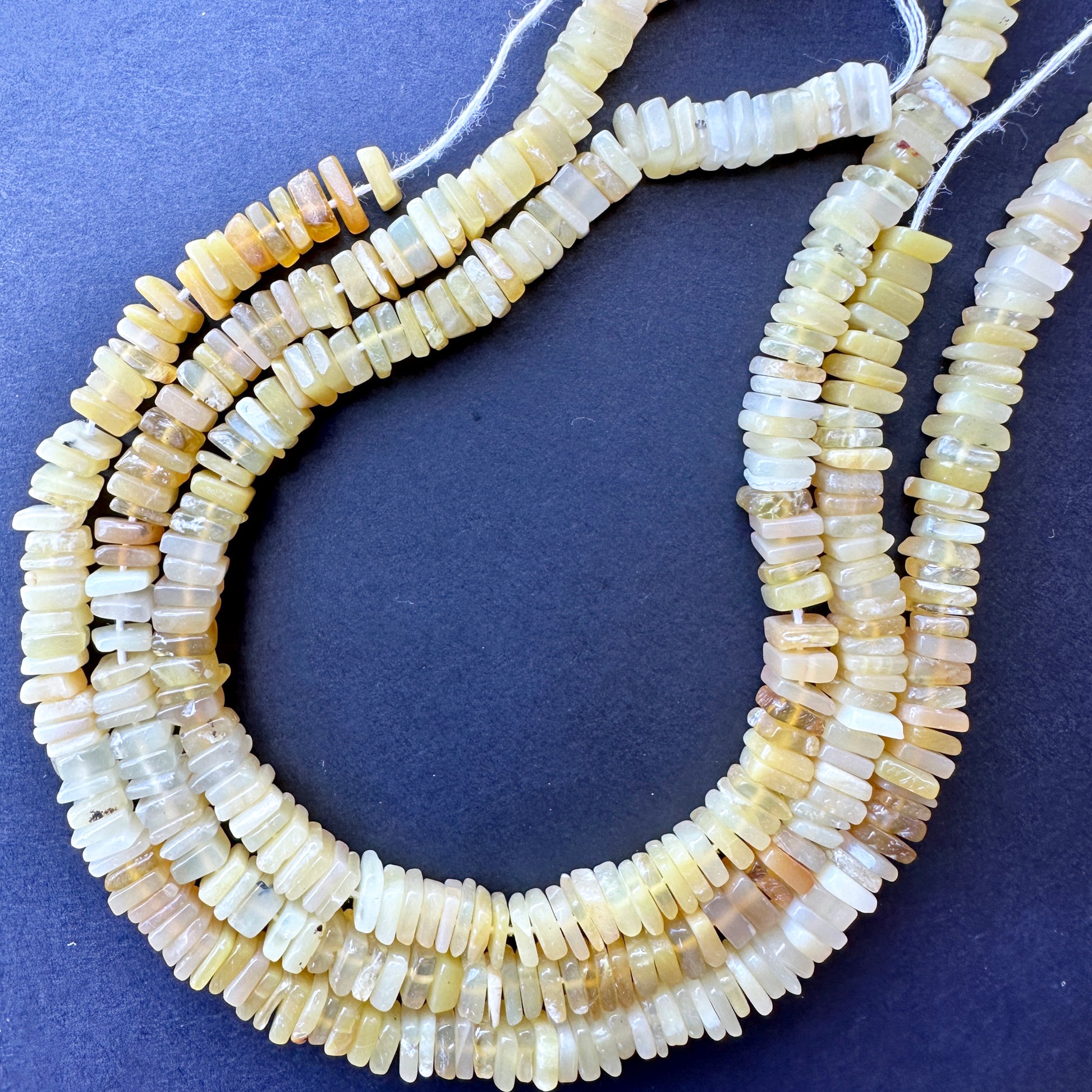 Close-up of natural gemstone beads in square cut with consistent sizing and polished surface for elegant jewellery making.