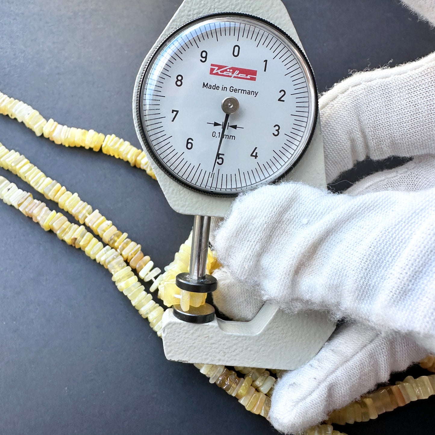 A dial gauge measures the yellow opal square 5.1mm gemstone.