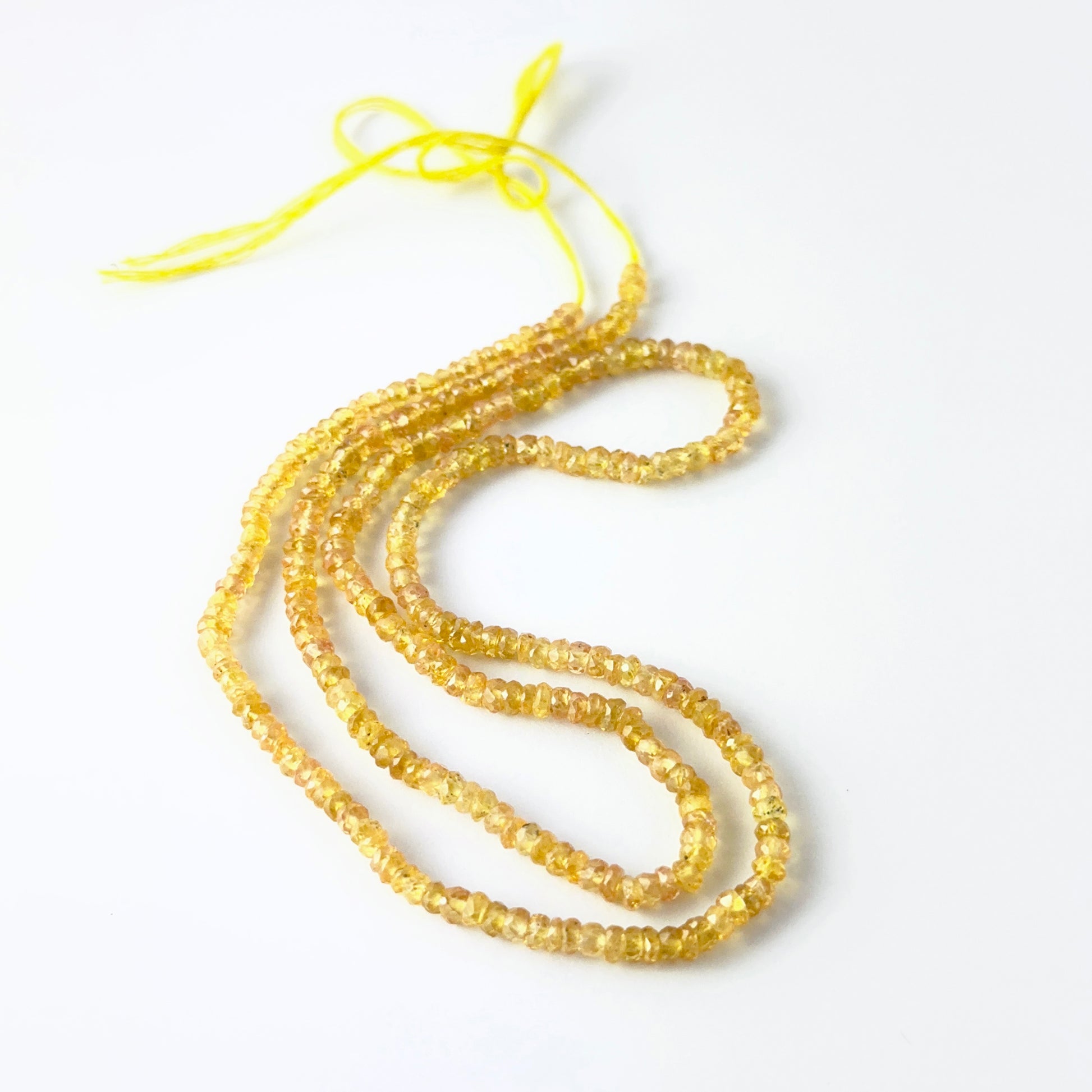 Faceted rondelle Yellow Sapphire beads arranged neatly, highlighting their polished finish and handmade jewellery component quality.