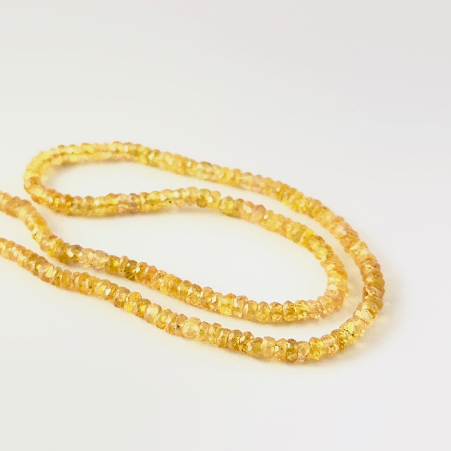 Close view of Yellow Sapphire faceted rondelle beads showing cut, clarity and premium gemstone quality.