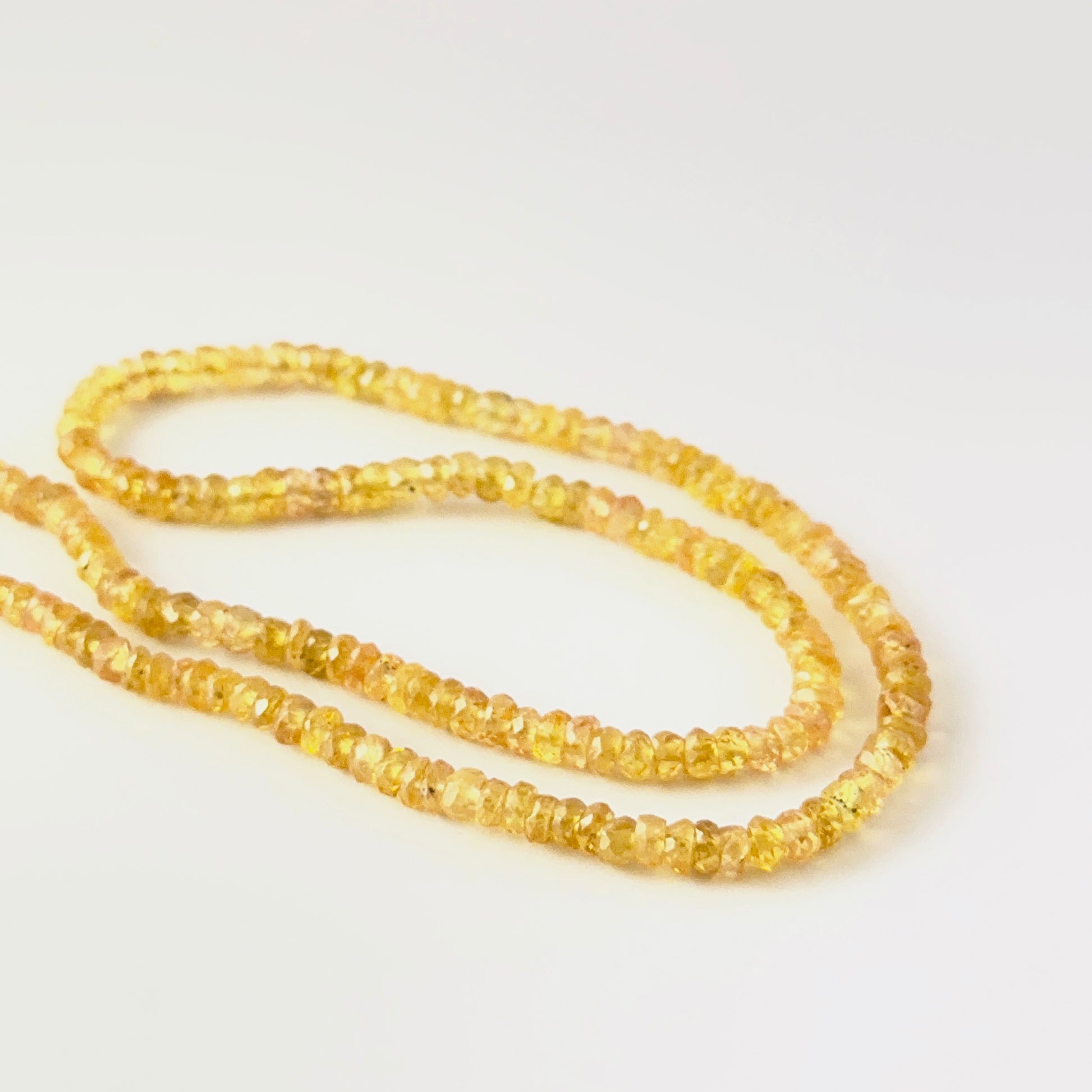 Close view of Yellow Sapphire faceted rondelle beads showing cut, clarity and premium gemstone quality.