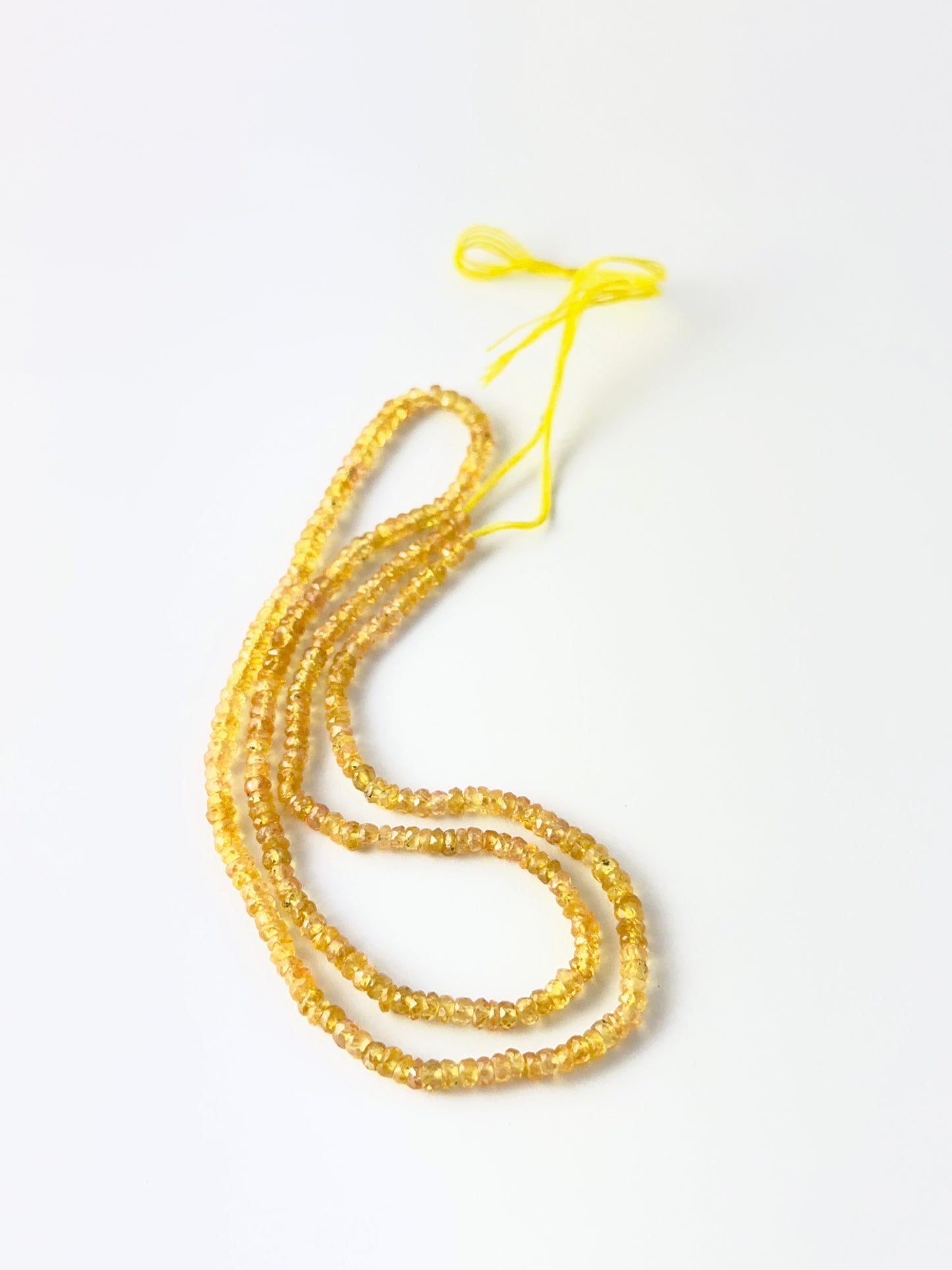 Yellow Sapphire faceted rondelle beads in a long strand, displaying warm tones and elegant handcrafted appeal.